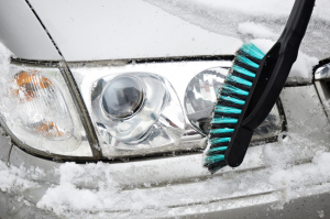 Man cleans car from snow with brush